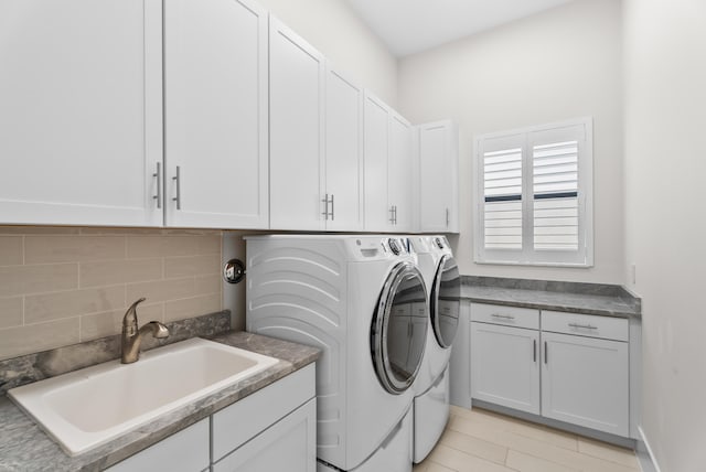 clothes washing area with washer and dryer, cabinet space, and a sink