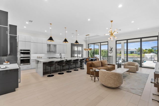 living room featuring recessed lighting, visible vents, a notable chandelier, and light wood finished floors