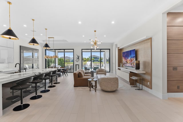 living room with a notable chandelier, recessed lighting, baseboards, and light wood finished floors