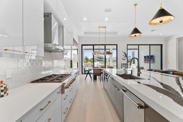 kitchen featuring a sink, stainless steel gas stovetop, dishwasher, wall chimney exhaust hood, and modern cabinets