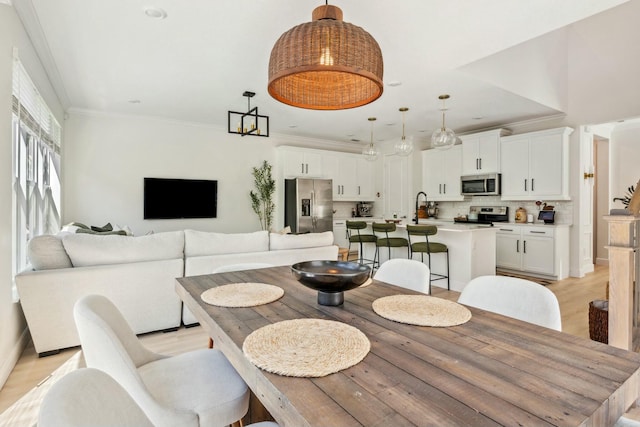 dining area with light wood-type flooring, crown molding, and baseboards