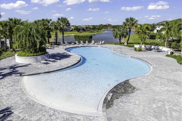 community pool featuring a water view, a patio, and fence