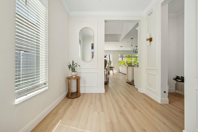 hallway featuring light wood-style flooring, baseboards, and ornamental molding