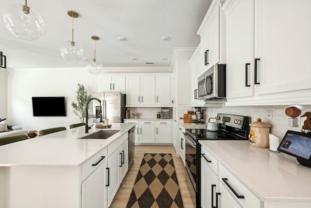 kitchen with backsplash, light countertops, appliances with stainless steel finishes, white cabinets, and a sink