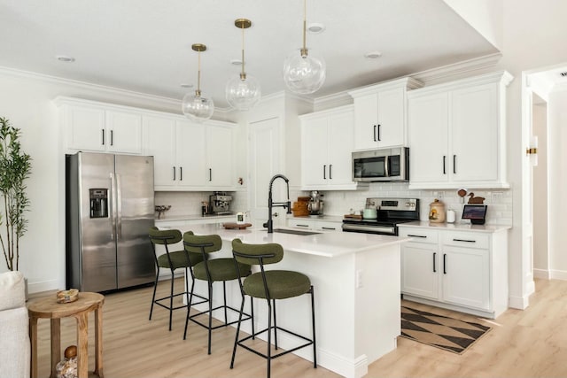 kitchen featuring a sink, a kitchen breakfast bar, appliances with stainless steel finishes, and ornamental molding