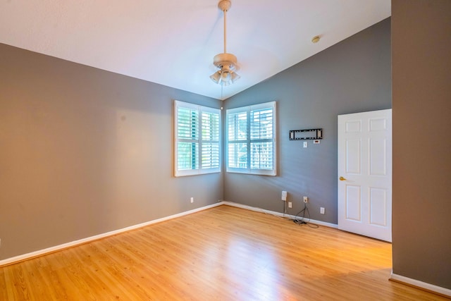 spare room with a ceiling fan, light wood-type flooring, baseboards, and vaulted ceiling