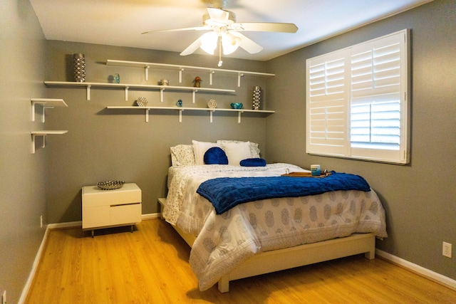 bedroom featuring baseboards, light wood-type flooring, and ceiling fan