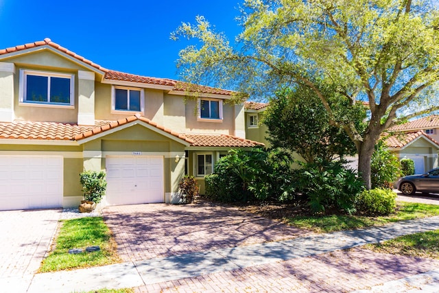 mediterranean / spanish-style home with decorative driveway, an attached garage, and stucco siding