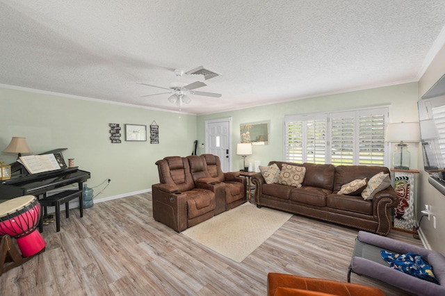 living room with wood finished floors, visible vents, baseboards, a textured ceiling, and crown molding