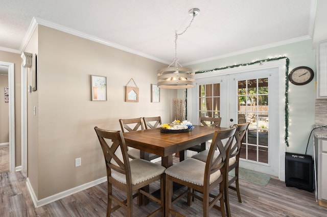 dining space with crown molding, wood finished floors, baseboards, and french doors