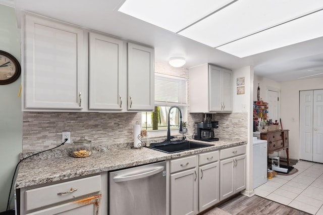 kitchen featuring stainless steel dishwasher, light tile patterned flooring, backsplash, and a sink