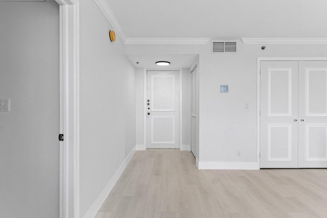 hallway featuring light wood-style flooring, baseboards, visible vents, and ornamental molding