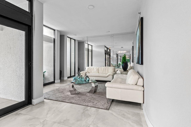 living room with a wall of windows, a textured wall, and baseboards