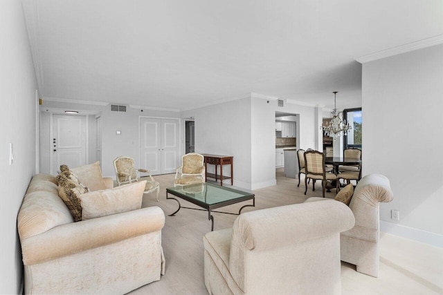 living room with visible vents, crown molding, light wood finished floors, baseboards, and a chandelier