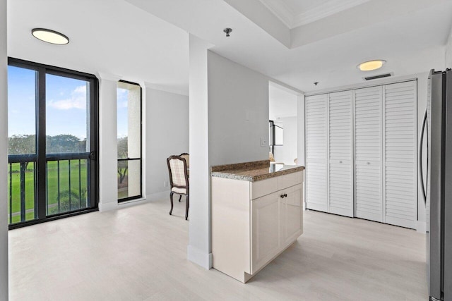 kitchen with a wall of windows, visible vents, light wood-style flooring, freestanding refrigerator, and ornamental molding