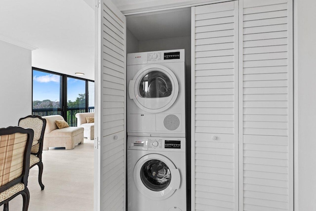 clothes washing area featuring laundry area, stacked washing maching and dryer, and wood finished floors