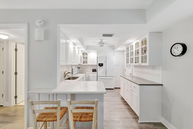 2400 S Ocean Dr Unit C623, Hutchinson Island, FL 34949 - kitchen with white refrigerator with ice dispenser, a raised ceiling, glass insert cabinets, light wood finished floors, and a peninsula
