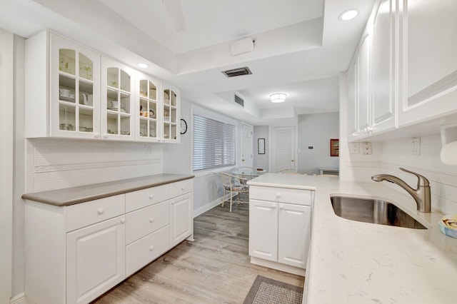 2400 S Ocean Dr Unit C623, Hutchinson Island, FL 34949 - kitchen with a sink, light wood-type flooring, white cabinetry, glass insert cabinets, and a tray ceiling