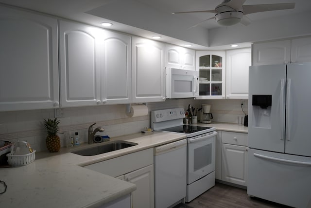 kitchen with white appliances, white cabinets, and a sink