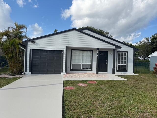 single story home featuring a garage, concrete driveway, and a front yard