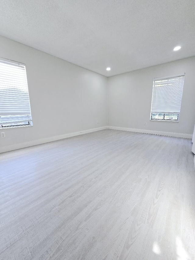 unfurnished room with recessed lighting, a textured ceiling, baseboards, and wood finished floors