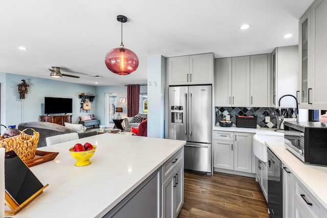 kitchen featuring gray cabinetry, tasteful backsplash, dark wood-style floors, stainless steel appliances, and light countertops