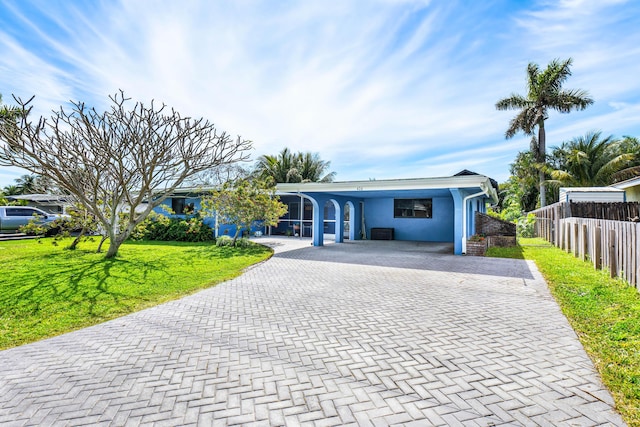 view of front of home with fence, a front yard, stucco siding, decorative driveway, and a carport