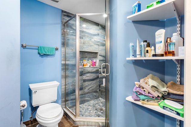 full bathroom featuring a stall shower, toilet, and wood finished floors