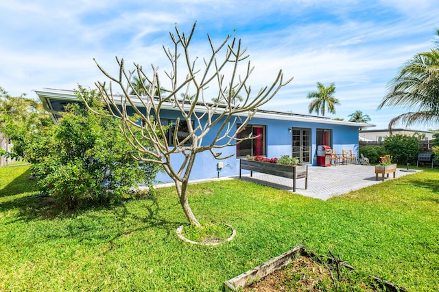 view of front of home featuring a patio area, stucco siding, and a front yard