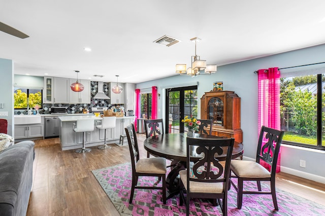 dining room with a notable chandelier, visible vents, light wood-type flooring, and baseboards