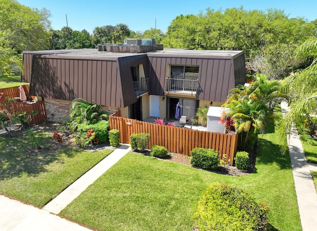 exterior space featuring a front yard, a balcony, and a fenced front yard