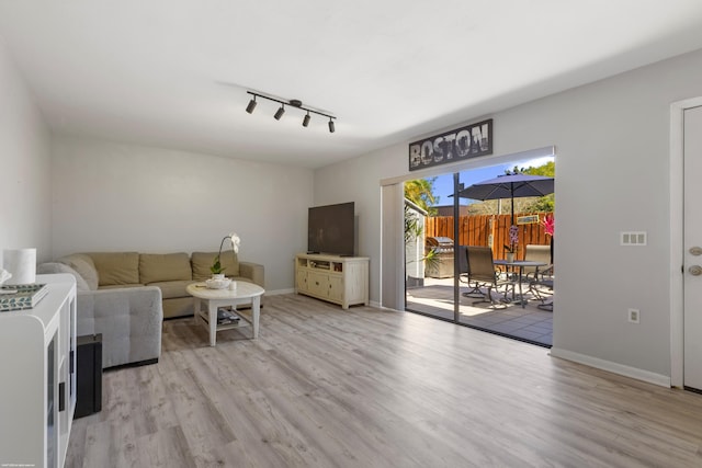 living room featuring track lighting, light wood-style flooring, and baseboards