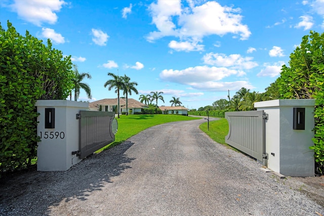 view of road with gravel driveway, a gate, and a gated entry