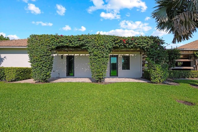 rear view of house featuring stucco siding and a yard