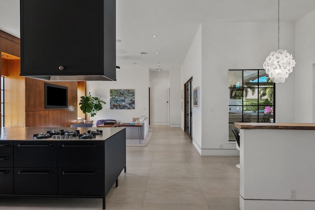 kitchen with modern cabinets, decorative light fixtures, dark cabinetry, light tile patterned floors, and stainless steel gas cooktop