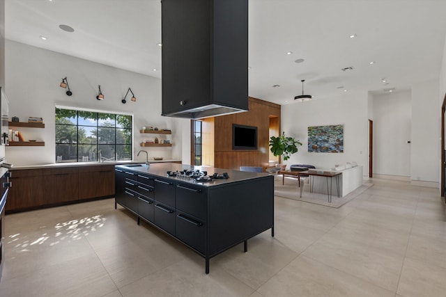 kitchen with a kitchen island, stainless steel gas cooktop, open shelves, a sink, and modern cabinets