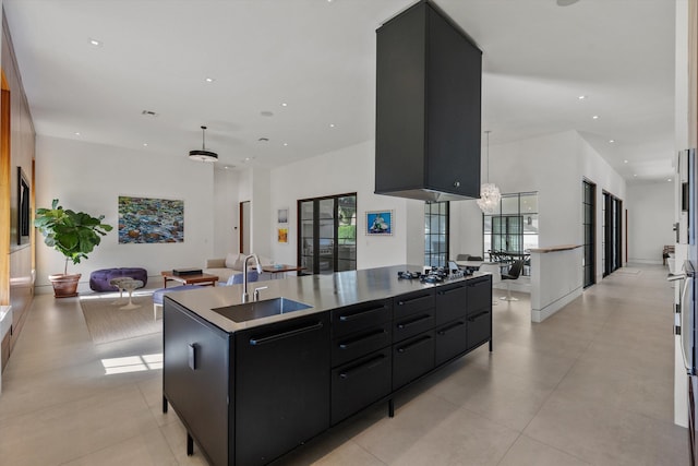 kitchen with a sink, a kitchen island, open floor plan, recessed lighting, and dark cabinets