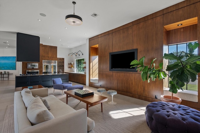 living area with recessed lighting, visible vents, and wood walls