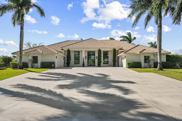 mediterranean / spanish home with stucco siding, a front lawn, concrete driveway, and an attached garage