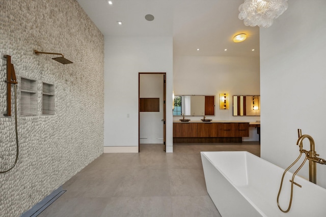 bathroom featuring vanity, recessed lighting, a freestanding bath, a towering ceiling, and an accent wall