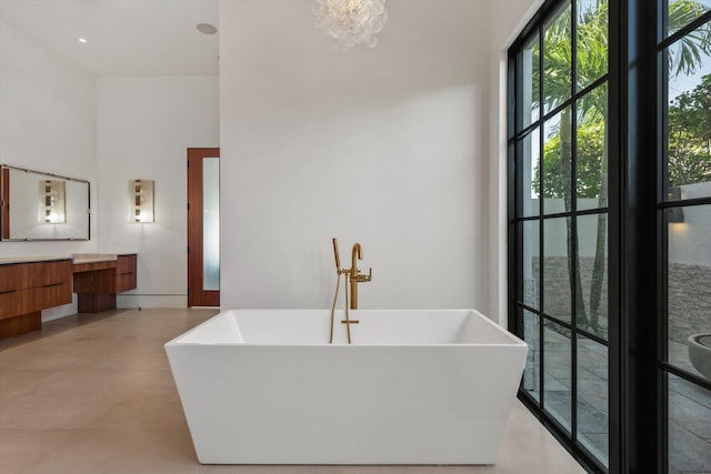 full bath featuring a freestanding bath, a towering ceiling, and vanity