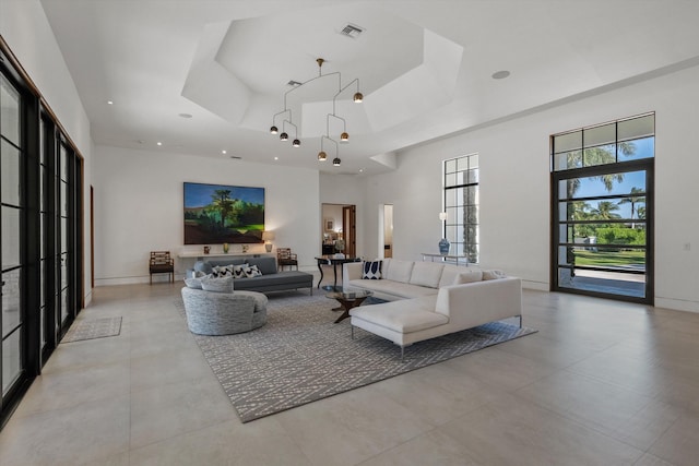 living room featuring visible vents, baseboards, a tray ceiling, recessed lighting, and a high ceiling