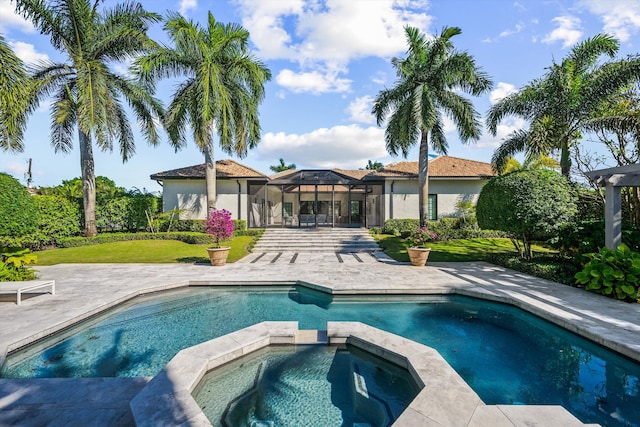 view of pool featuring a lanai, a yard, a patio area, and a pool with connected hot tub