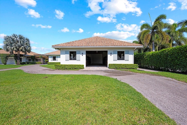 view of front facade featuring an attached garage, a tiled roof, a front yard, stucco siding, and driveway