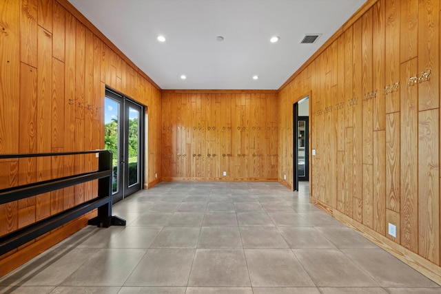 spare room with crown molding, wooden walls, and visible vents