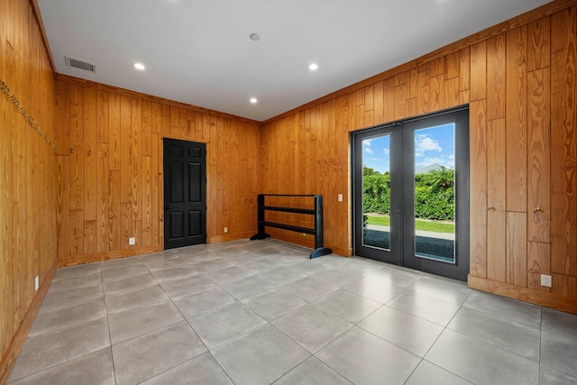 spare room featuring light tile patterned floors, visible vents, wood walls, and french doors