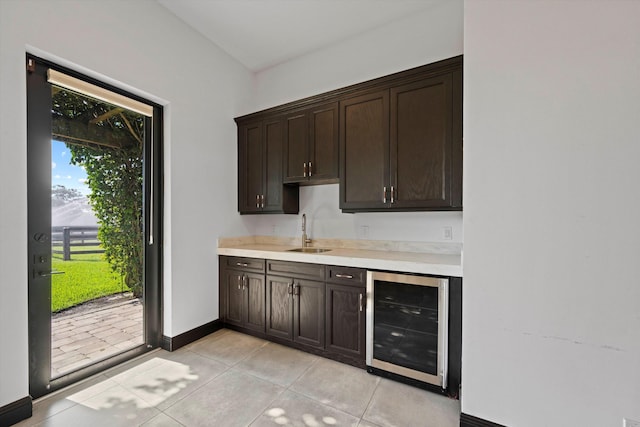 kitchen featuring light tile patterned floors, a sink, light countertops, wine cooler, and dark brown cabinetry