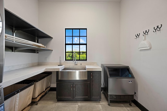 kitchen featuring baseboards, open shelves, light tile patterned flooring, a sink, and light countertops