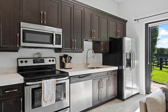 kitchen featuring light countertops, dark brown cabinetry, appliances with stainless steel finishes, and a sink