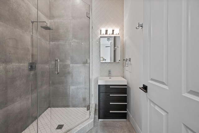 full bathroom with vanity, baseboards, a stall shower, tile walls, and backsplash